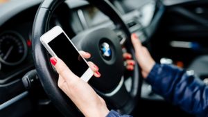 Žena za volantem BMW s mobilem v ruce